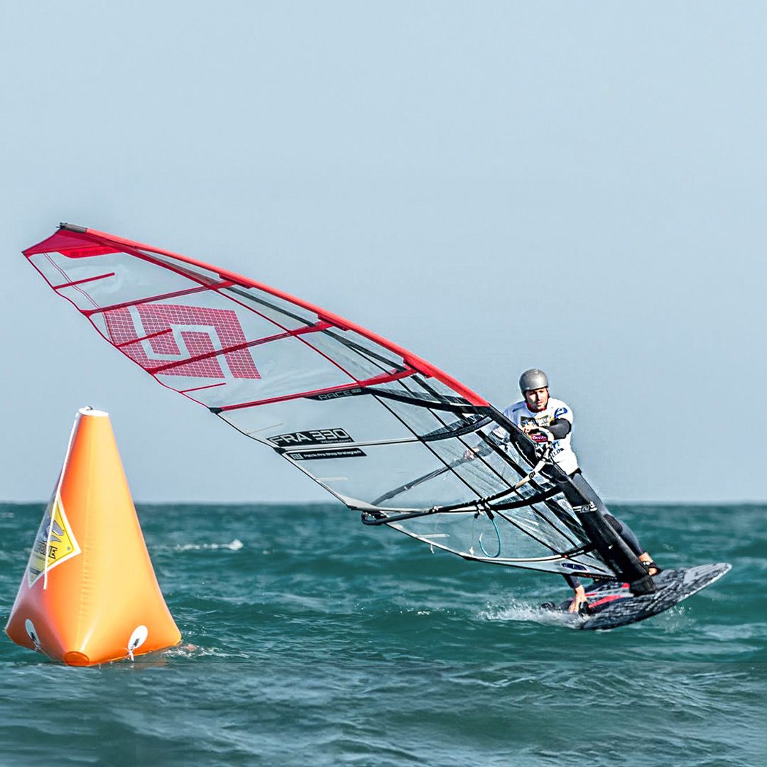 Patrik Race HA Gen2 Windsurfboard mit rotem Segel, Athlet in Aktion auf dem Wasser, Seitenansicht