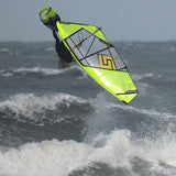 Patrik 4-Wave LTD Wavesegel in Neongelb und Grau, in Aktion auf dem Wasser mit Wellen im Hintergrund