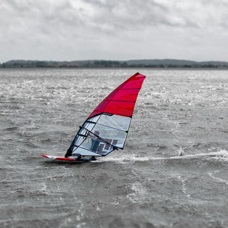 Patrik Race MA Gen2 Windsurfboard mit rotem Segel im Wasser, Seitenansicht