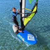 Patrik Micro Ride Windsurf-Board blau mit neongelb-grünem Segel, Kind beim Windsurfen im Wasser