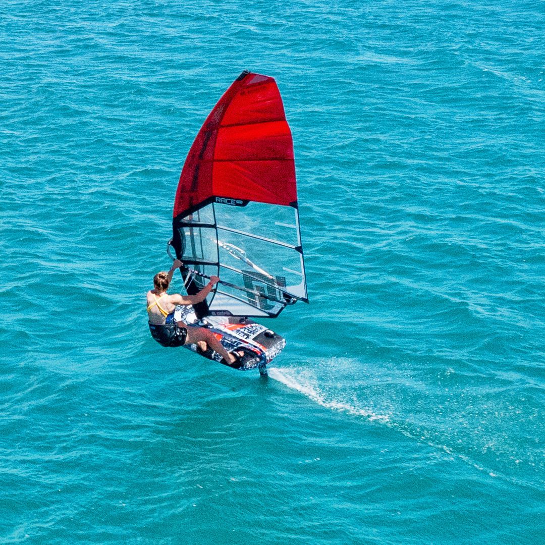 Patrik Race MA Gen2 Windsurfboard mit rotem Segel auf türkisblauem Wasser, Draufsicht