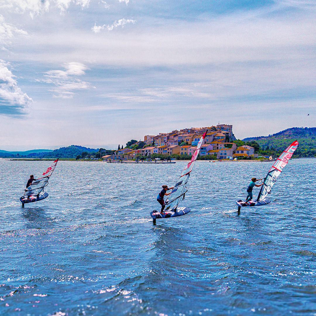 Patrik Race HA Gen2 Windsurfboard in Aktion auf dem Wasser mit Windsurfern in Küstenlandschaft