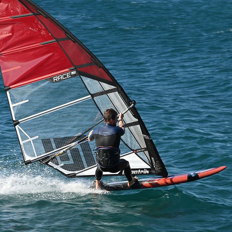 Patrik Slalom Windsurfboard rot-schwarz mit rotem Segel, Athlet in Aktion auf dem Wasser
