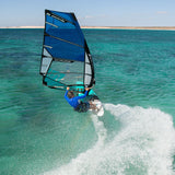 Patrik X-Cross Windsurfboard blau in Aktion auf türkisem Meer mit Wellen, Frontalansicht